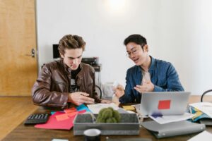 Two men sat in front of a computer chatting