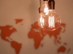 A lightbulb hanging down from the ceiling with a map of the world on the wall in the background